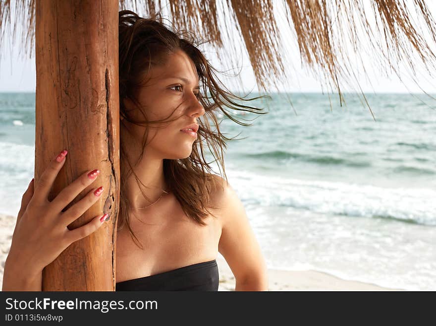 Portrait of girl on beach under beach umbrella; sea on background. Portrait of girl on beach under beach umbrella; sea on background