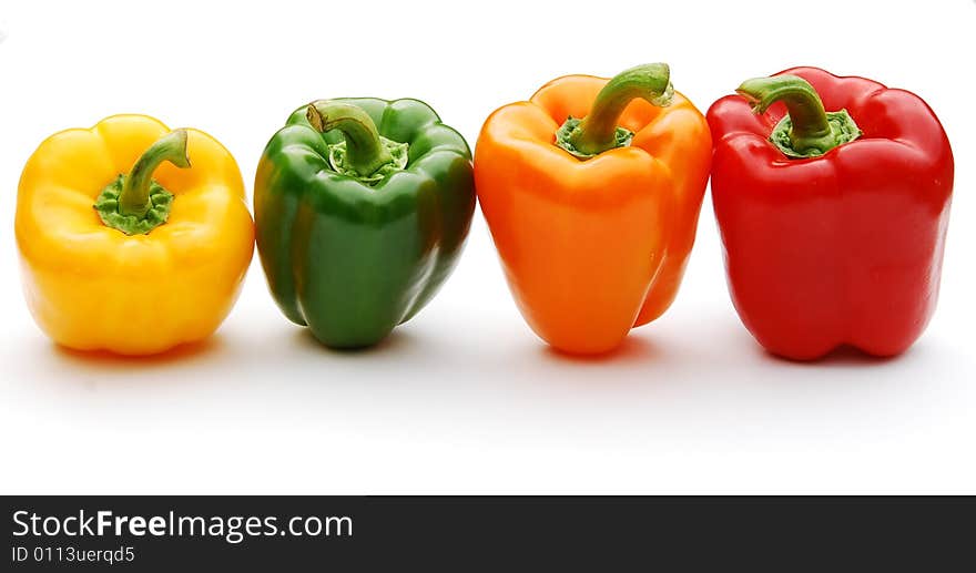 Shot of a four differnt coloured peppers in a row isolated on white