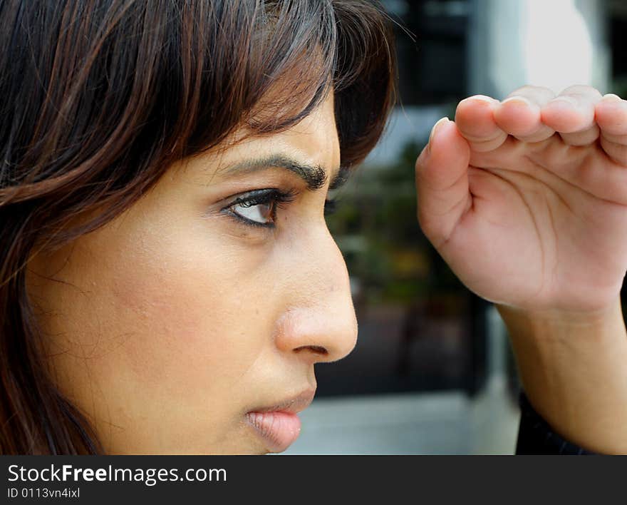 Woman looking with her hand covering the light over hey eyes. Woman looking with her hand covering the light over hey eyes.