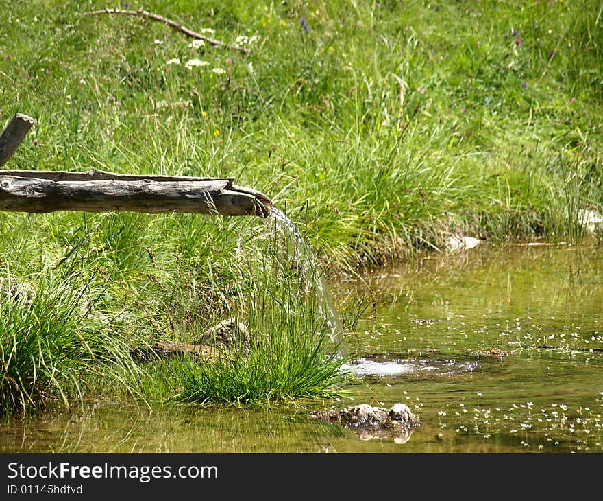 An image of a wood pipe for water in a mountain's little lake