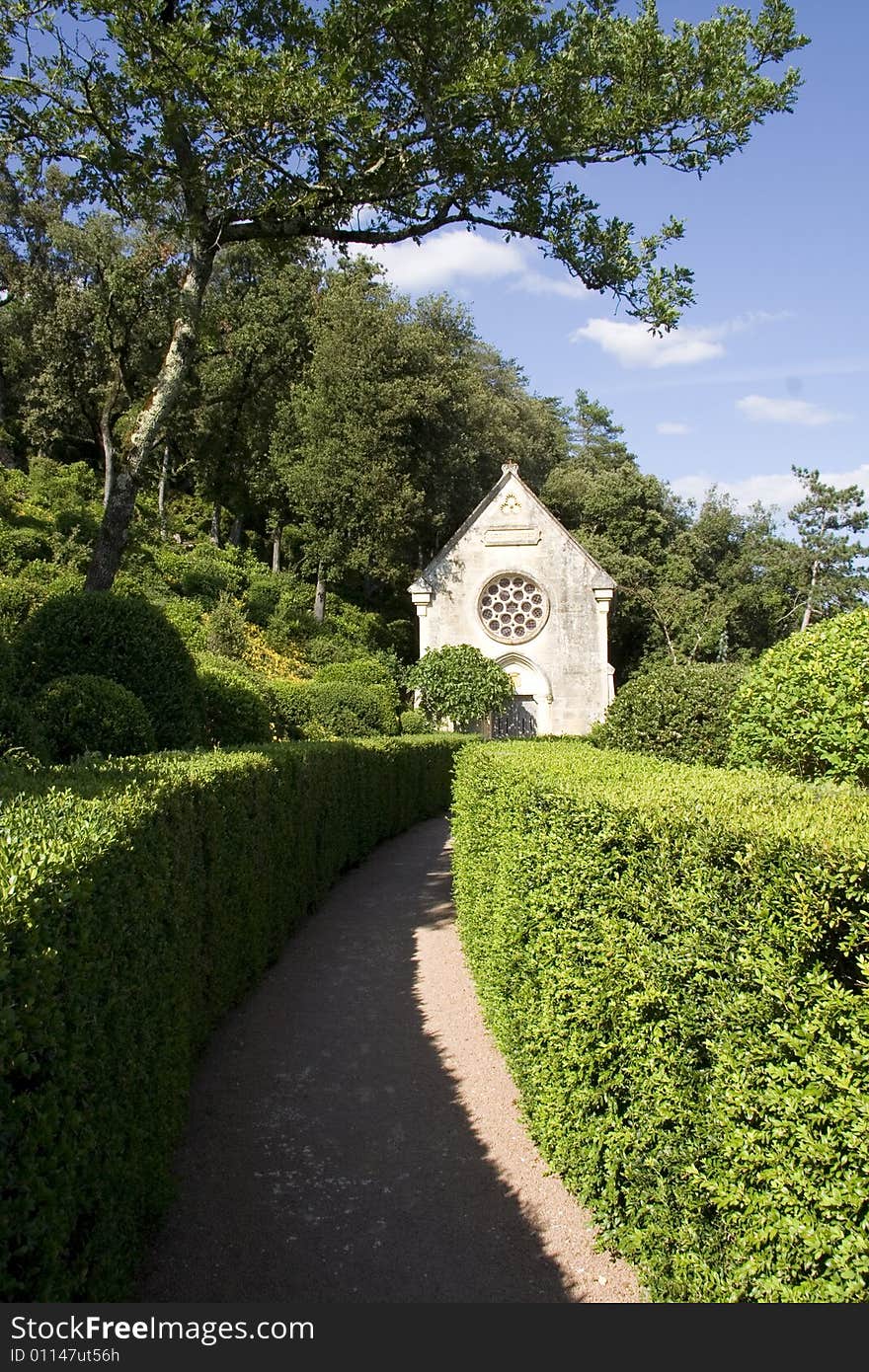 Curved pathway through neat hedges to a small stone church. Curved pathway through neat hedges to a small stone church