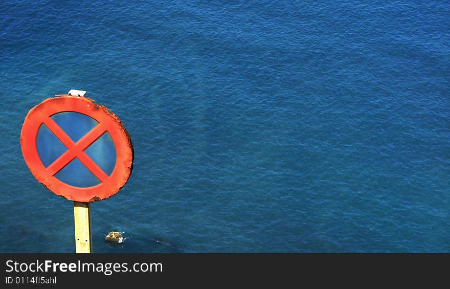 No parking sign post with blue sea in the background