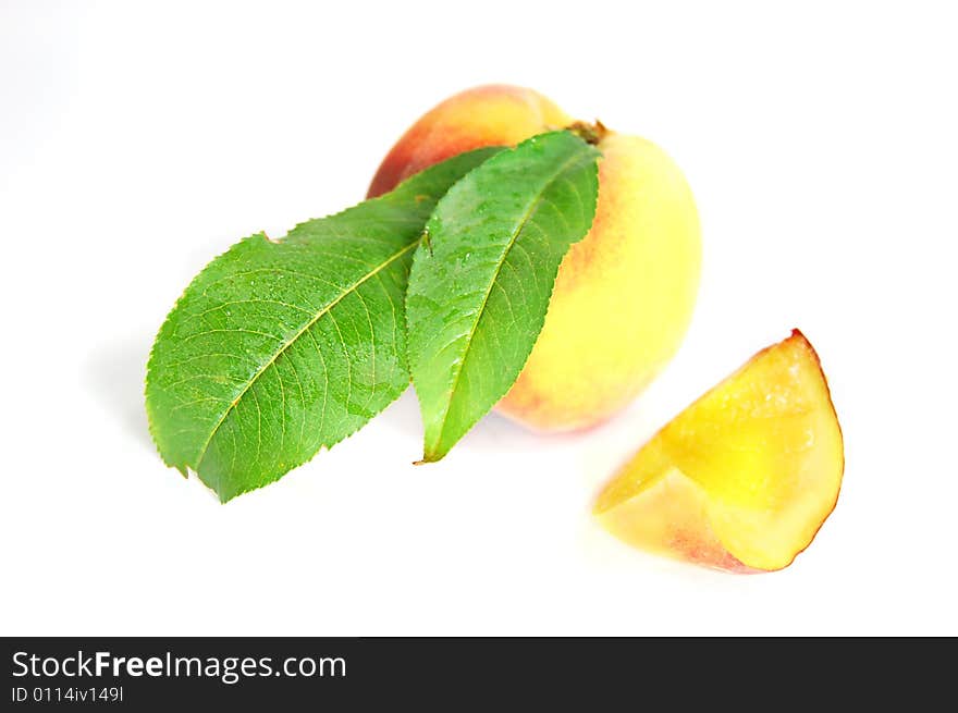 Ripe peach fruit with green leafs isolated on white