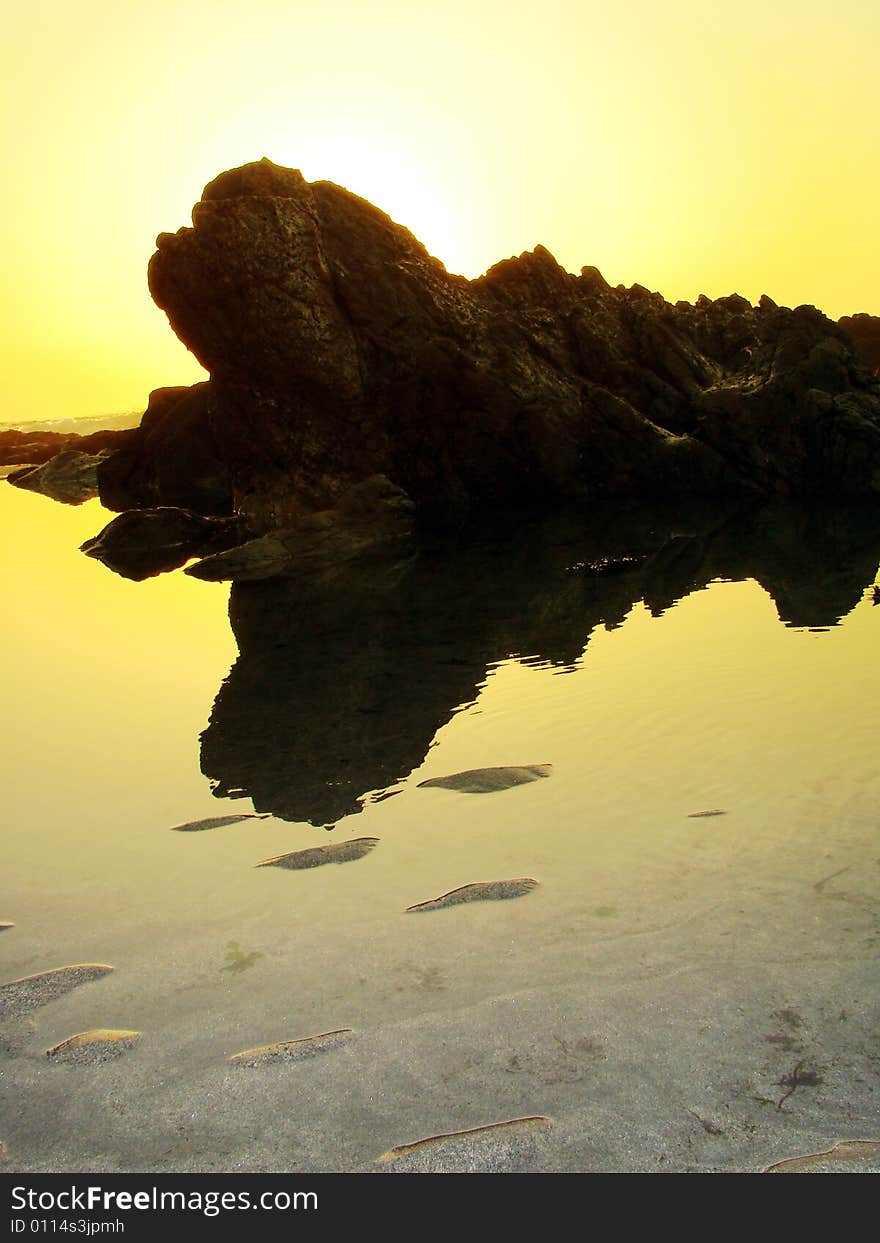 Rock reflection at sunset near the ocean