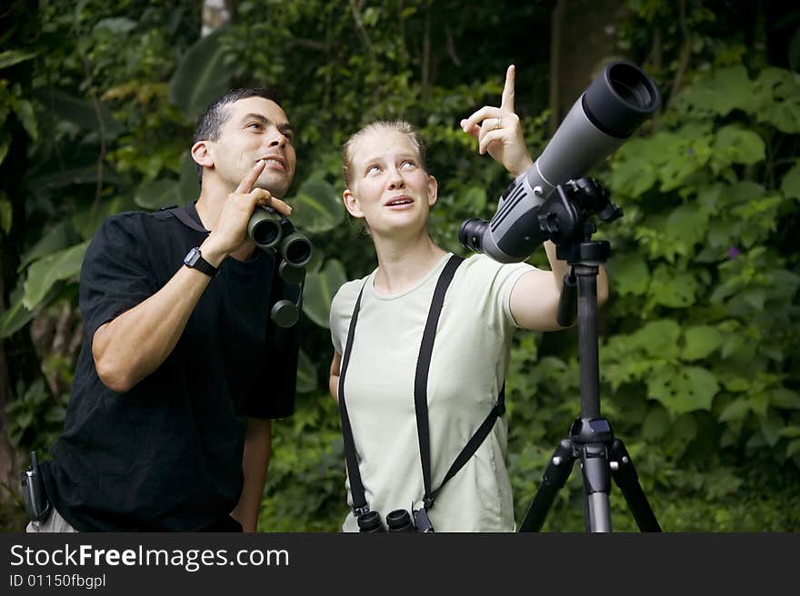 Pretty Woman with Binoculars and Man with Telescope in Rain Forest Jungle