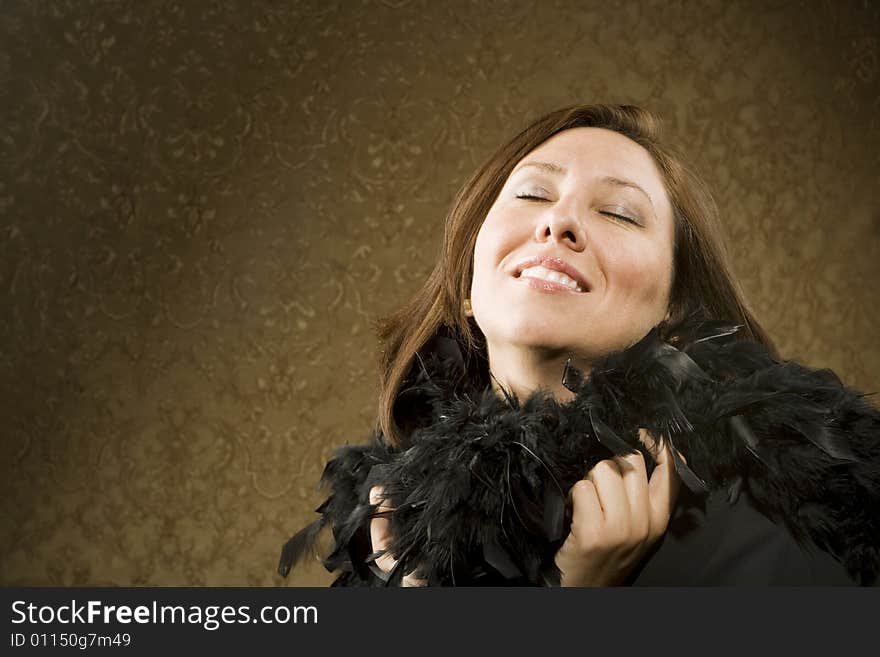 Pretty Hispanic Woman Wearing a Feather Boa in front of Gold Wallpaper. Pretty Hispanic Woman Wearing a Feather Boa in front of Gold Wallpaper