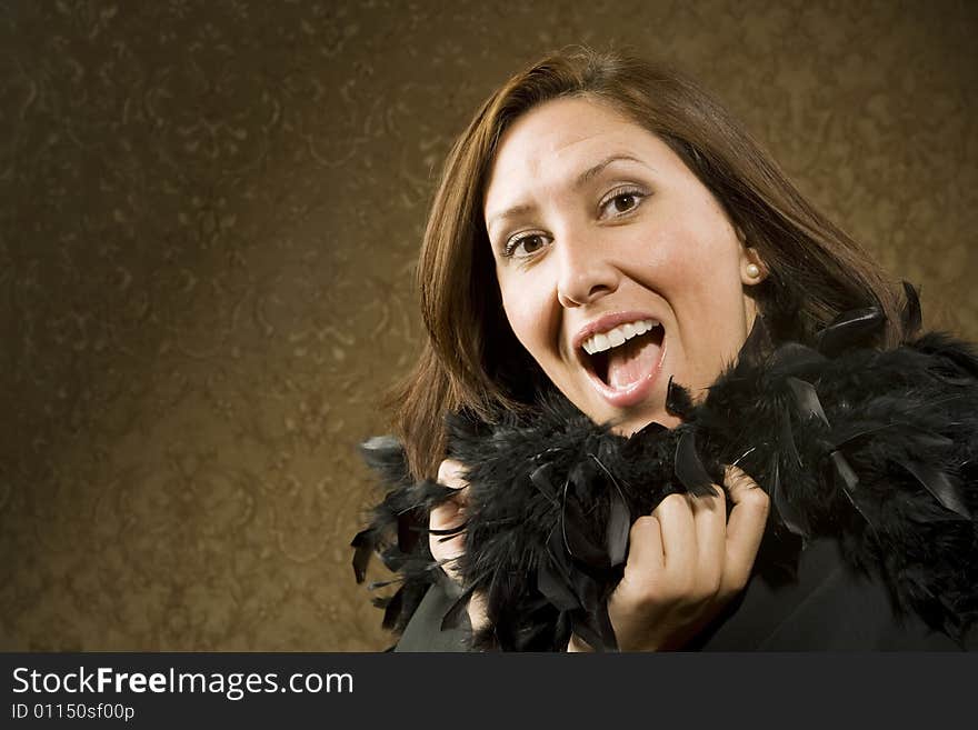 Pretty Hispanic Woman Wearing a Feather Boa in front of Gold Wallpaper. Pretty Hispanic Woman Wearing a Feather Boa in front of Gold Wallpaper