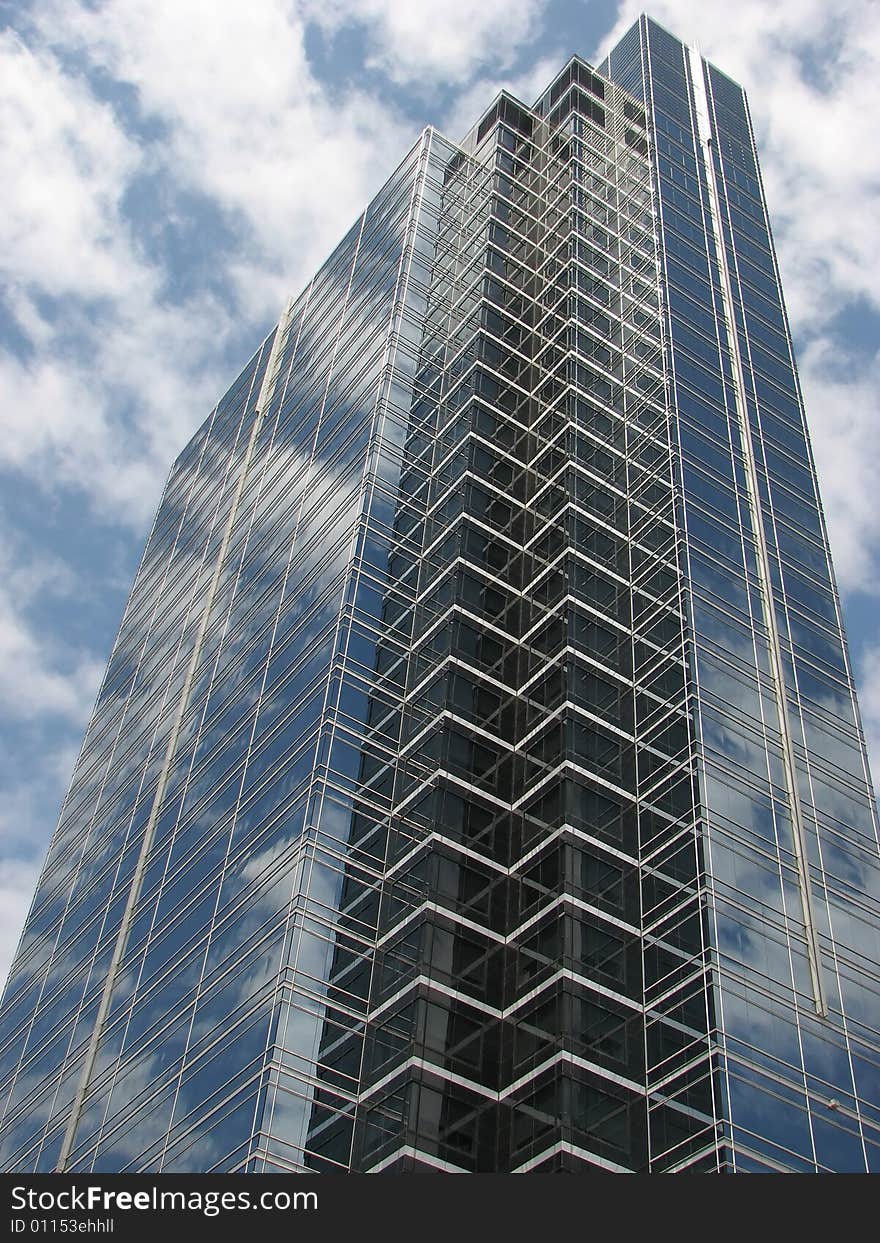 Fluffy white clouds and deep blue sky reflecting in the windows of a skyscraper. Fluffy white clouds and deep blue sky reflecting in the windows of a skyscraper.