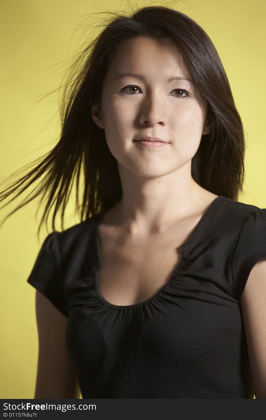 Vertical head ans shoulders portrait of young Asian woman against a yellow background. Vertical head ans shoulders portrait of young Asian woman against a yellow background.