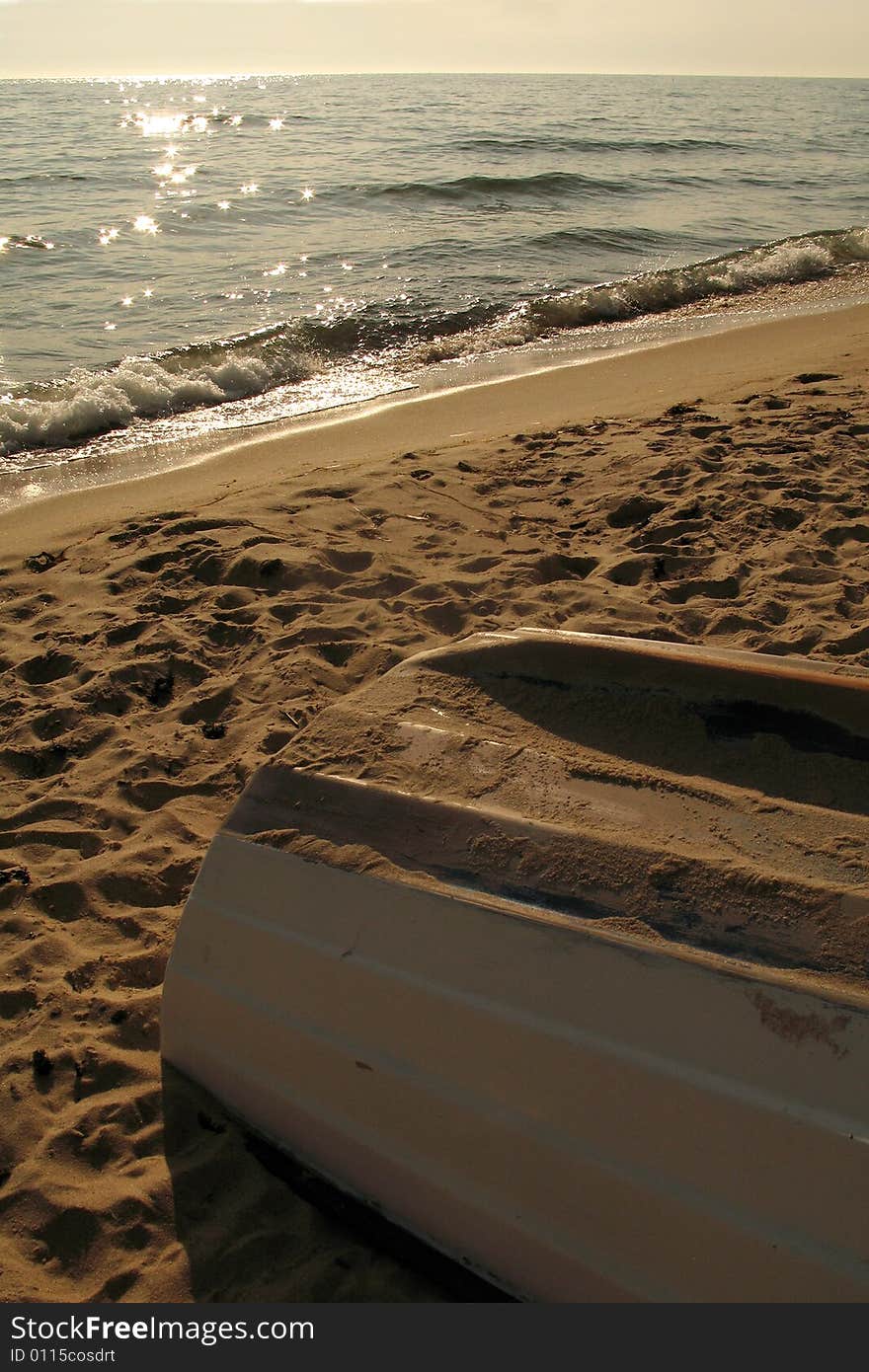 A boat laying on the beach upside down at sunset. A boat laying on the beach upside down at sunset