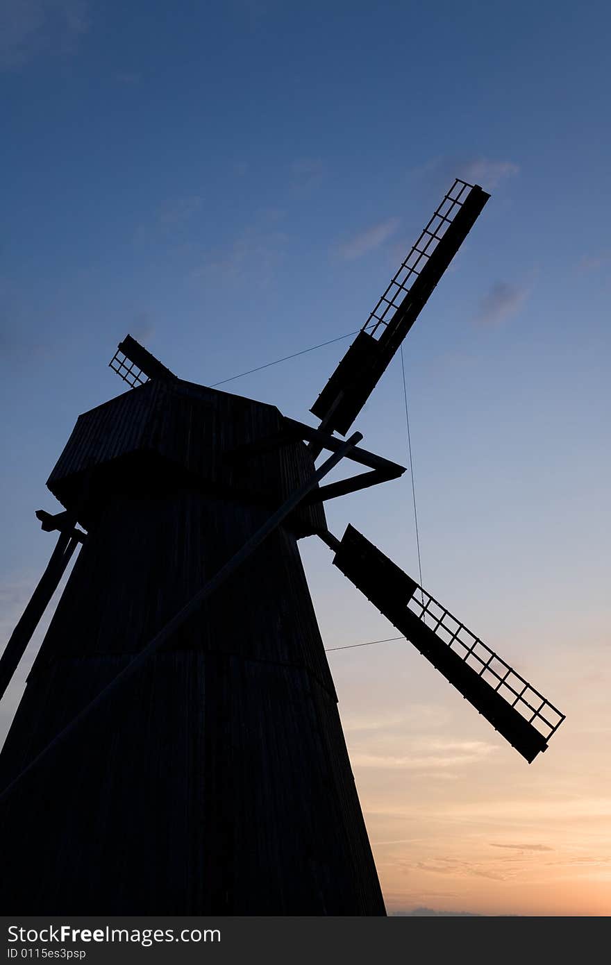 Silhouette of an old windmill on a background of sunset