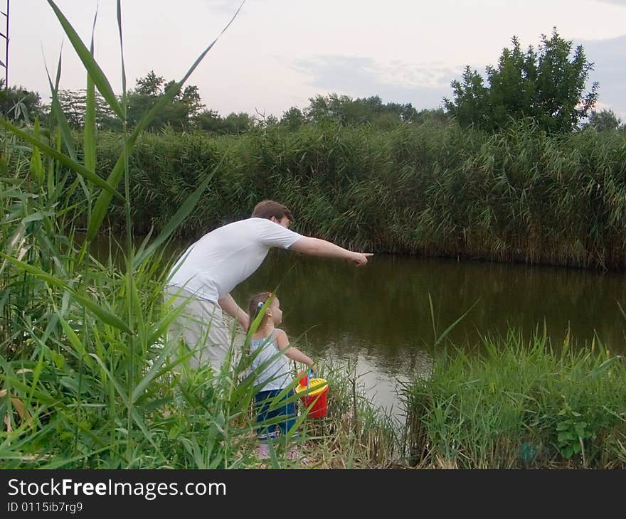 A dad and daughter go for a walk near the river. A dad and daughter go for a walk near the river