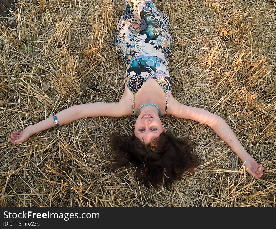 Young lady lying in straw smiling arms outstretched. Young lady lying in straw smiling arms outstretched