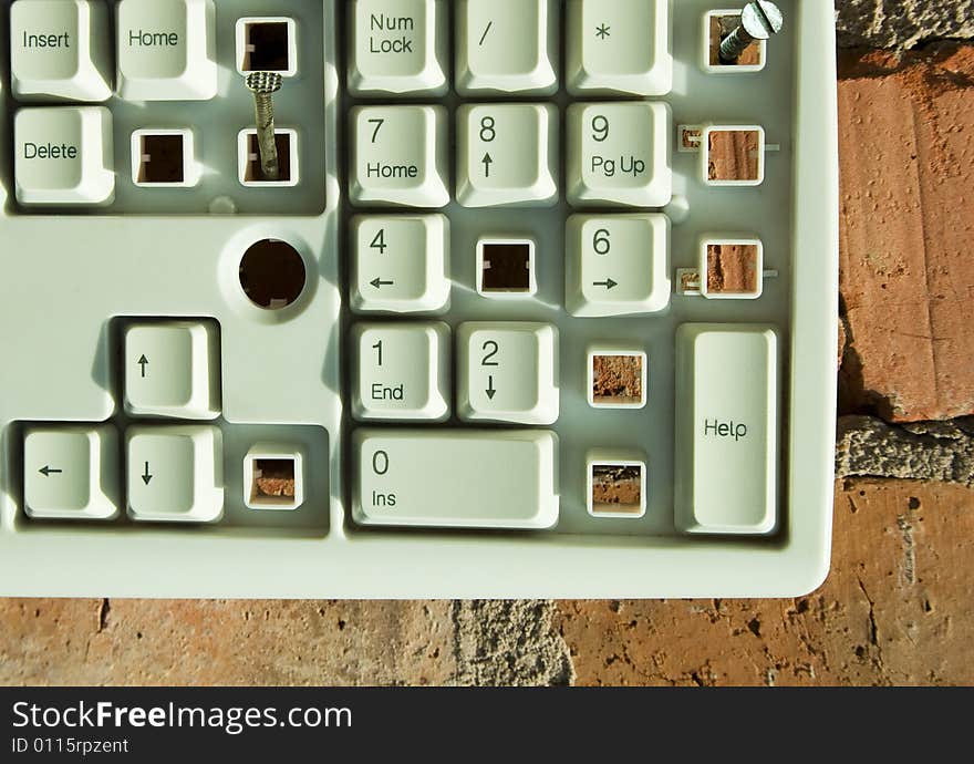 Disassembled keyboard with white button on the brick wall