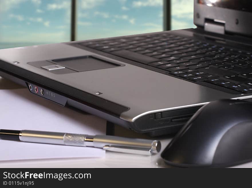 Close-up of a laptop, pen and mouse at an office. Close-up of a laptop, pen and mouse at an office