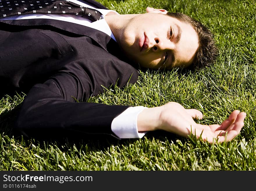 Businessman resting over the grass. Businessman resting over the grass