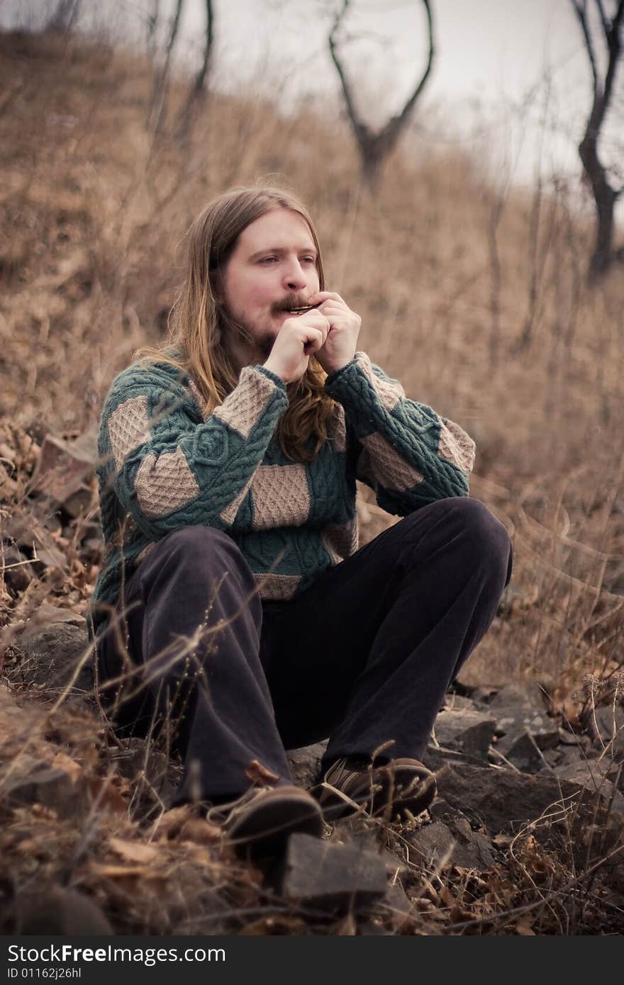 Young man relaxing outdoors playing on a homus (Jews Harp). Young man relaxing outdoors playing on a homus (Jews Harp)