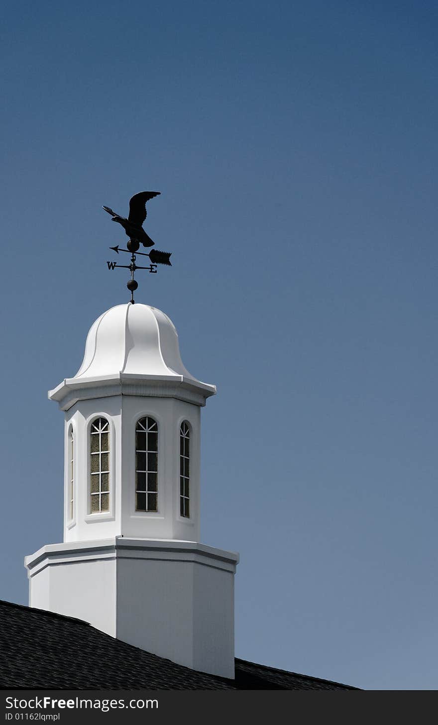 White cupola and weather vane against blue sky. White cupola and weather vane against blue sky.