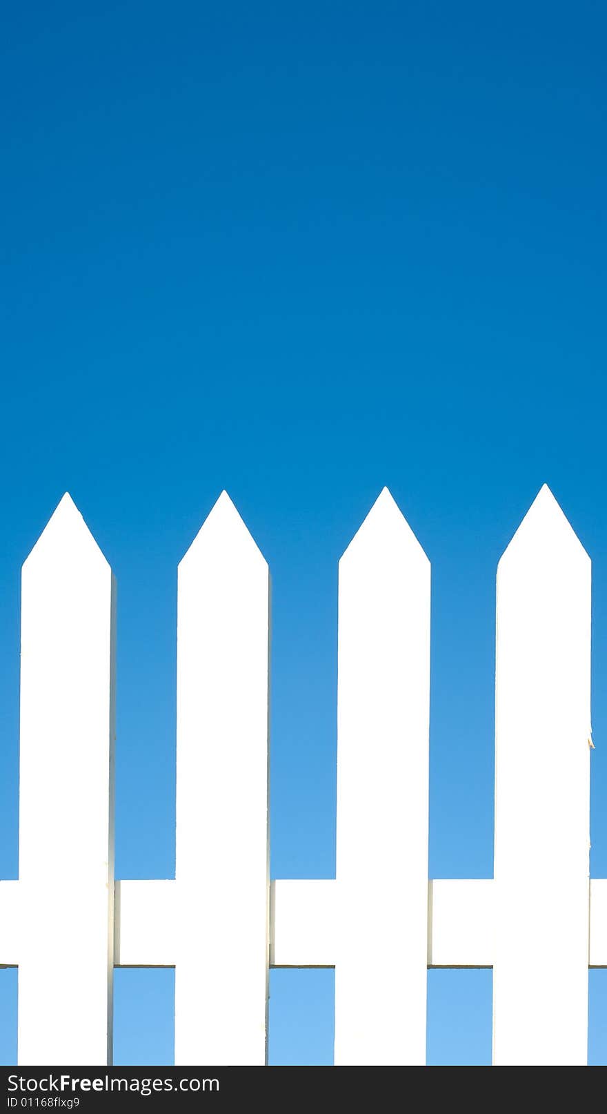 A white picket fence background in front of a bright blue sky with copy space.