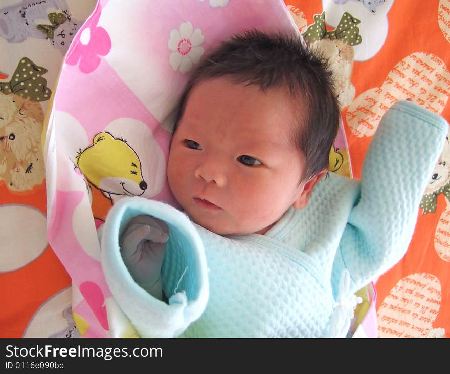 An infant on a bed facing the windows