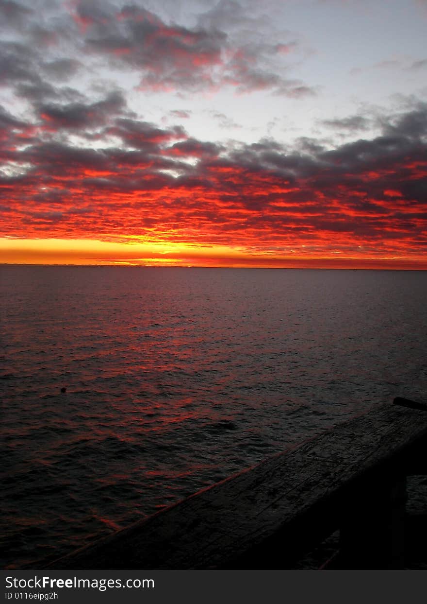 Orange clouds as the sun rises over the ocean. Orange clouds as the sun rises over the ocean