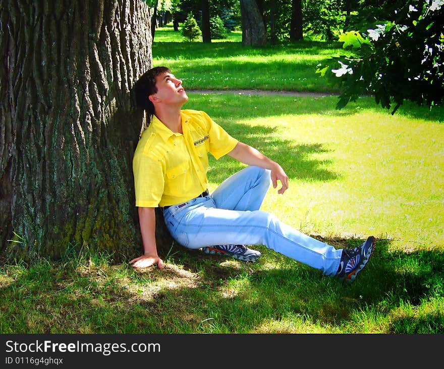 Photo of the young man under a big tree.