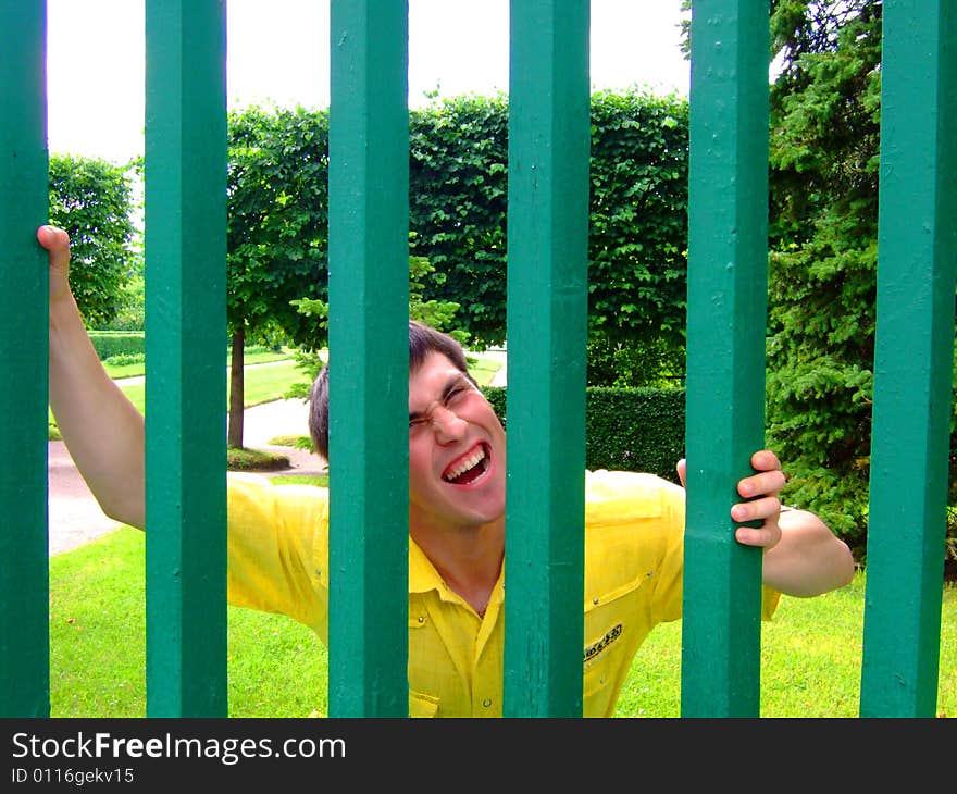 Photo of the young man behind a green fence.