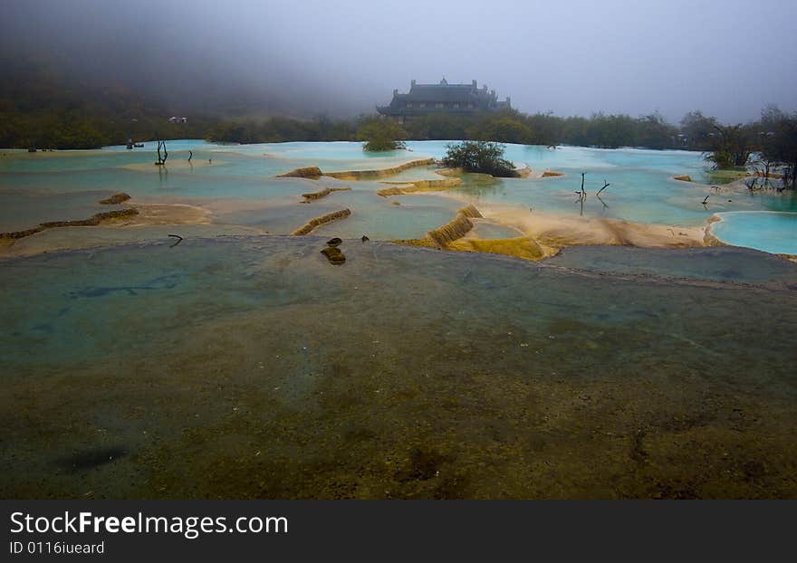 The color full pool in rain,with chinese temple in background,Huanglong scenic area,Sichuan,china. The color full pool in rain,with chinese temple in background,Huanglong scenic area,Sichuan,china