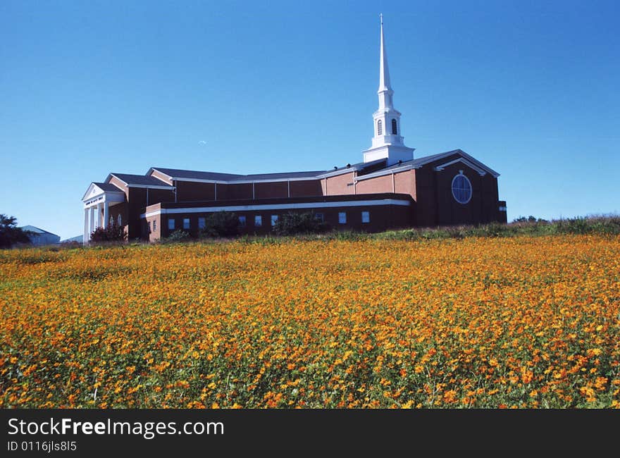 Photo of a church on a hill with orange flowers in the foreground. Photo of a church on a hill with orange flowers in the foreground.