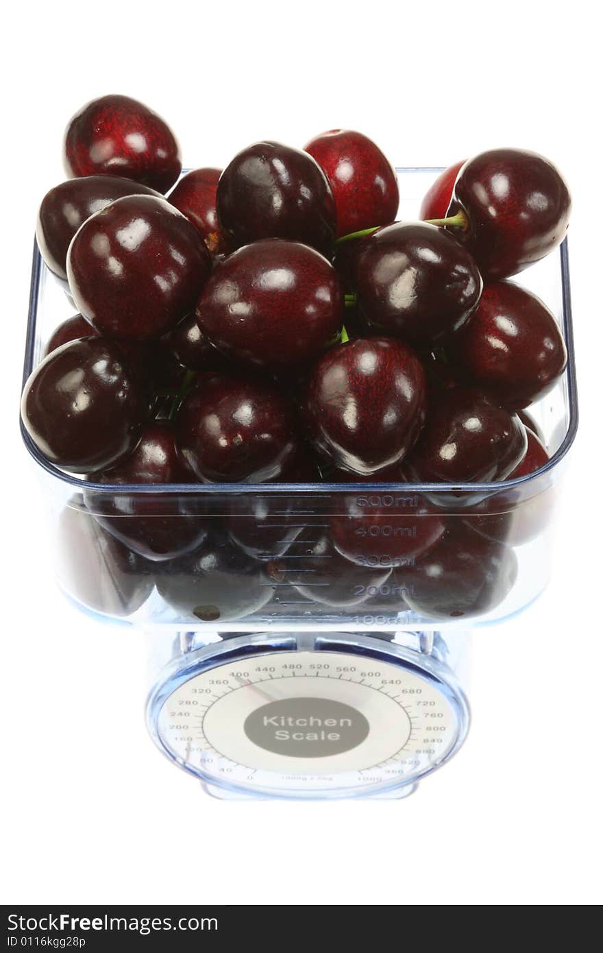 Kitchen scales and cherries on a white background. Kitchen scales and cherries on a white background.