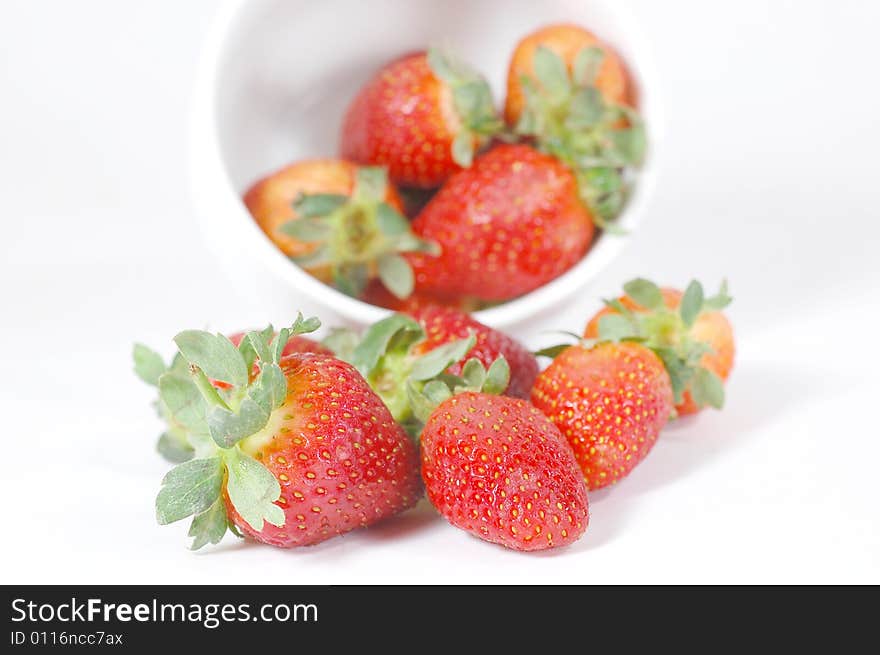 Strawberries pourring out of a bowl isolated on white