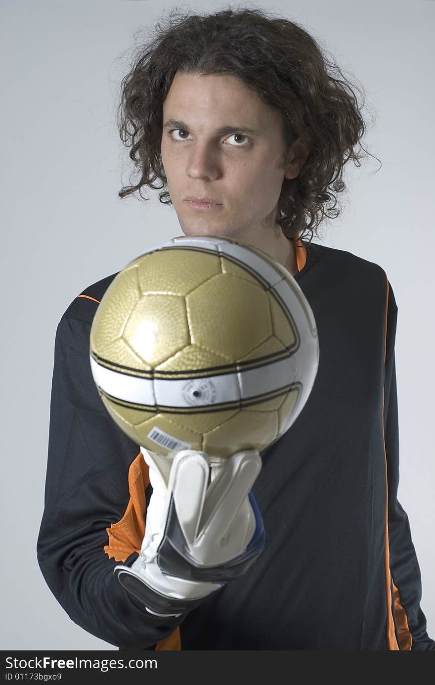 Man with a serious expression holds a soccer ball out in front of him. Vertically framed photograph. Man with a serious expression holds a soccer ball out in front of him. Vertically framed photograph.