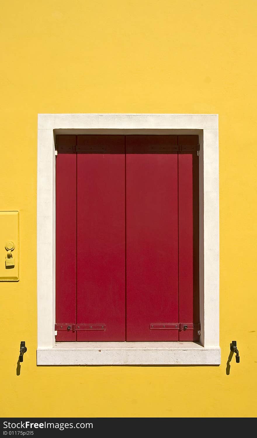 Yellow wall with a red window-shutters. Yellow wall with a red window-shutters