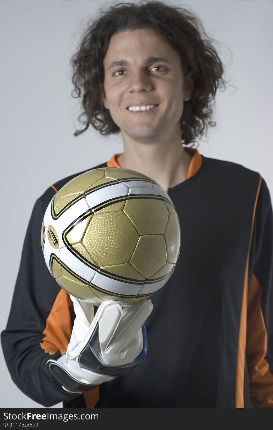 Soccer goalie wearing a jersey and gloves smiles as he holds a soccer ball. Vertically framed photograph. Soccer goalie wearing a jersey and gloves smiles as he holds a soccer ball. Vertically framed photograph