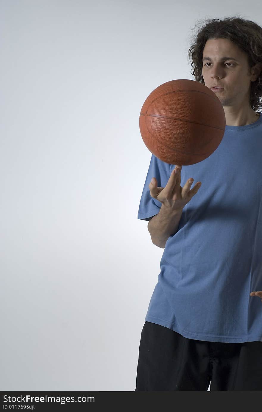 A male figure balancing a basketball on two fingers.  He is staring at the ball. Vertically framed shot. A male figure balancing a basketball on two fingers.  He is staring at the ball. Vertically framed shot.