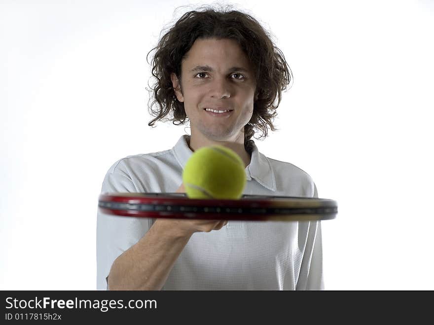 Man with a smile on his face holds a tennis racket and balances a tennis ball on top of it. Horizontally framed photograph. Man with a smile on his face holds a tennis racket and balances a tennis ball on top of it. Horizontally framed photograph