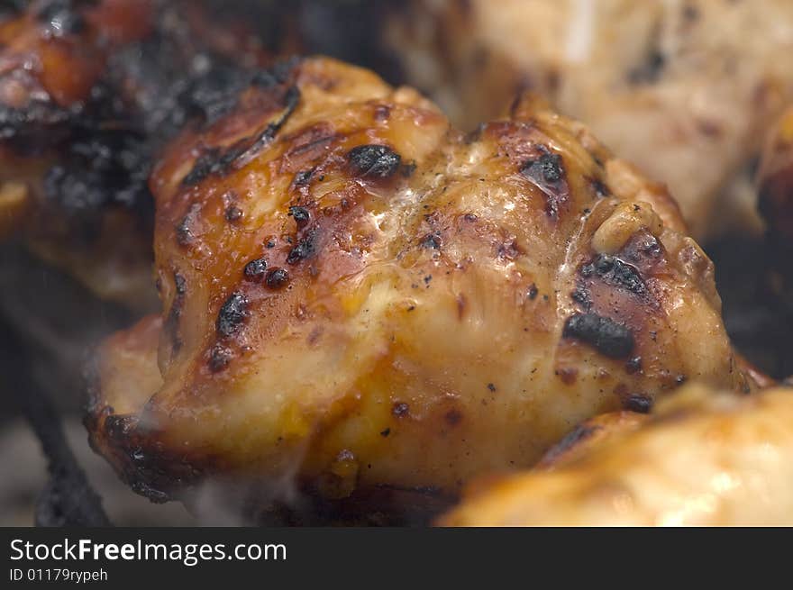 Chicken pieces being grilled on charcoals of hibachi grill. Chicken pieces being grilled on charcoals of hibachi grill.