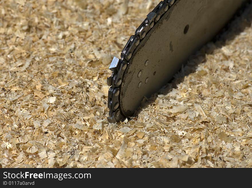 Detail of the chain saw on the background of sawdust.