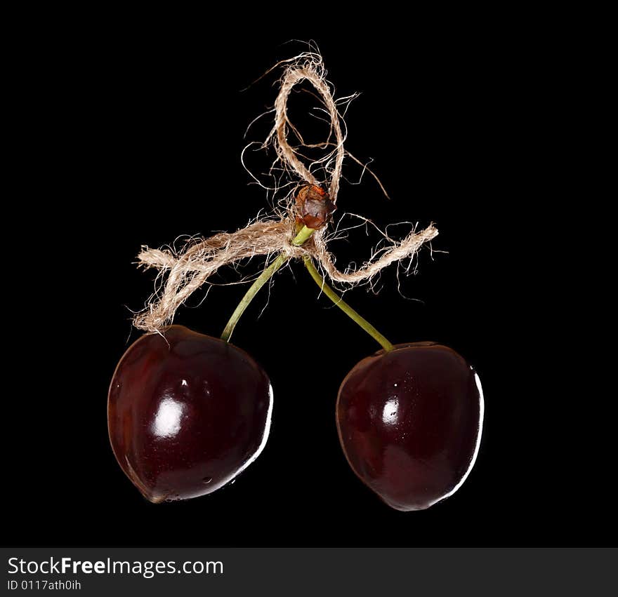 Two cherryes tied by rope, over black background. Two cherryes tied by rope, over black background