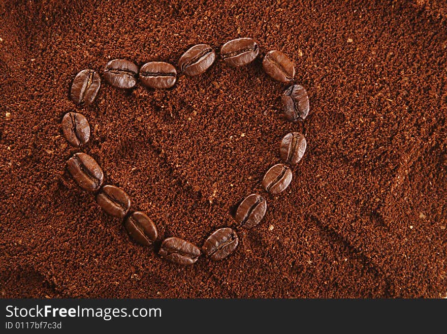 Coffee beans in heart shape and ground background