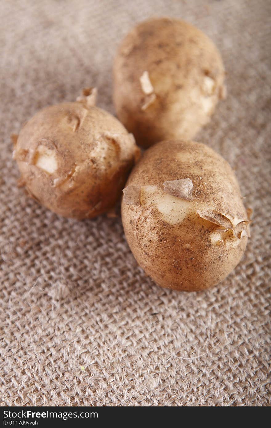 Three white new potatoes on brown hessian rustic