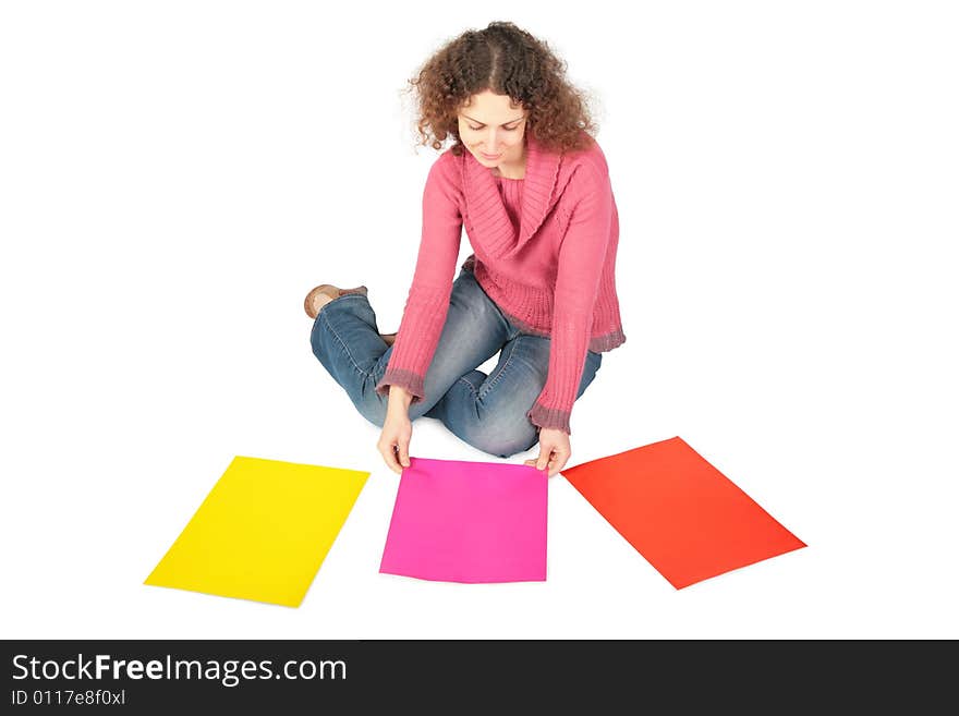 Young woman sits on floor with three multi-coloured sheets of paper