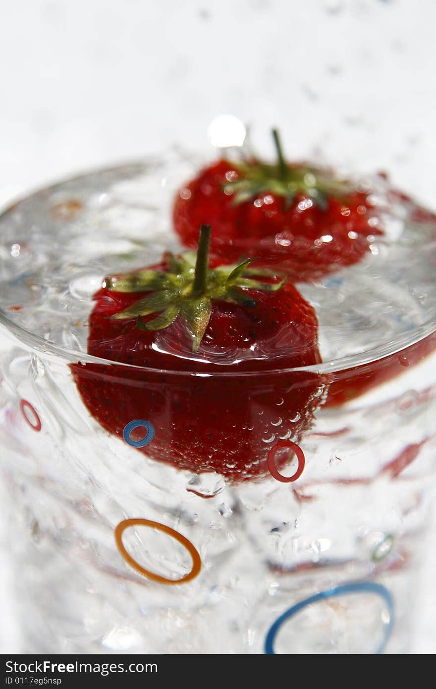 Water glass ice cube and strawberries with waterdrops on background, close-up, shallow FOF