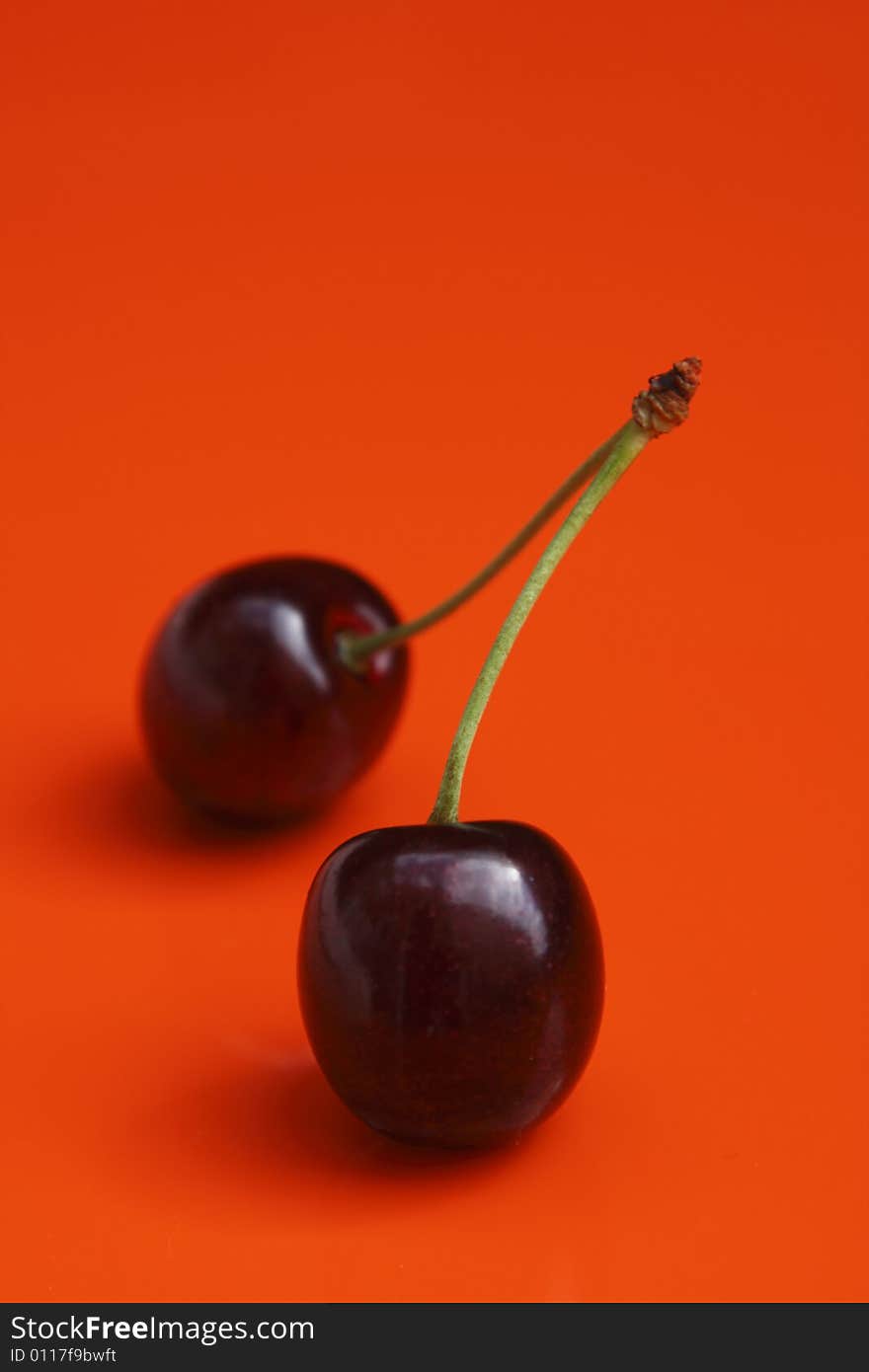 Two cherries on vivid orange background