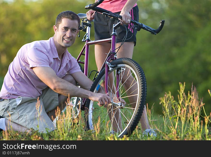 Close up of a man crouching down next to a bike smiling. Horizontally framed shot. Close up of a man crouching down next to a bike smiling. Horizontally framed shot.