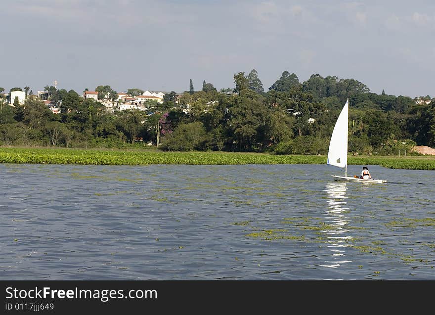 A young couple is sailing on a lake together.  They are looking away from the camera.  Horizontally framed shot. A young couple is sailing on a lake together.  They are looking away from the camera.  Horizontally framed shot.