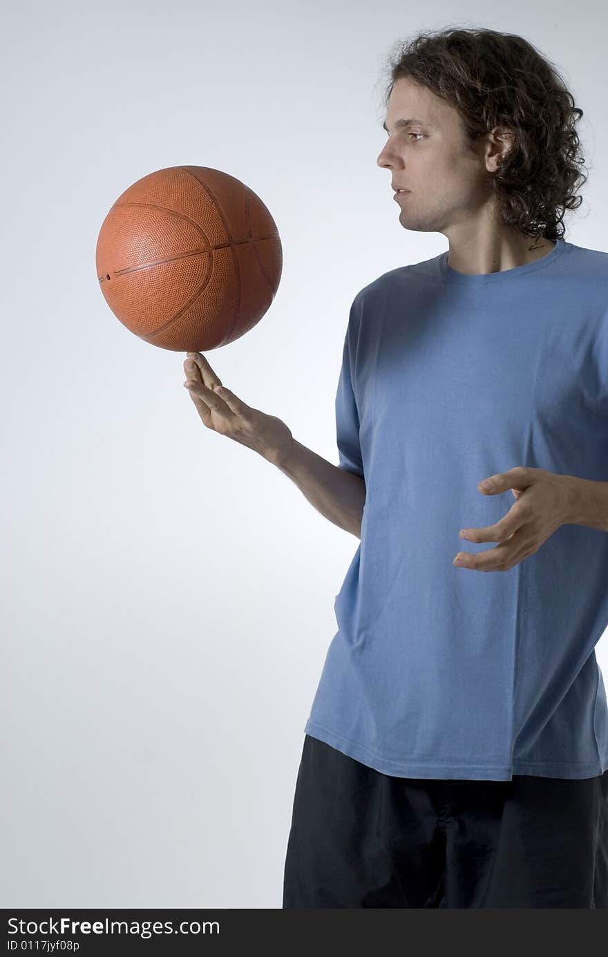 Man concentrates while balancing a basketball on his finger - Vertically framed photograph. Man concentrates while balancing a basketball on his finger - Vertically framed photograph