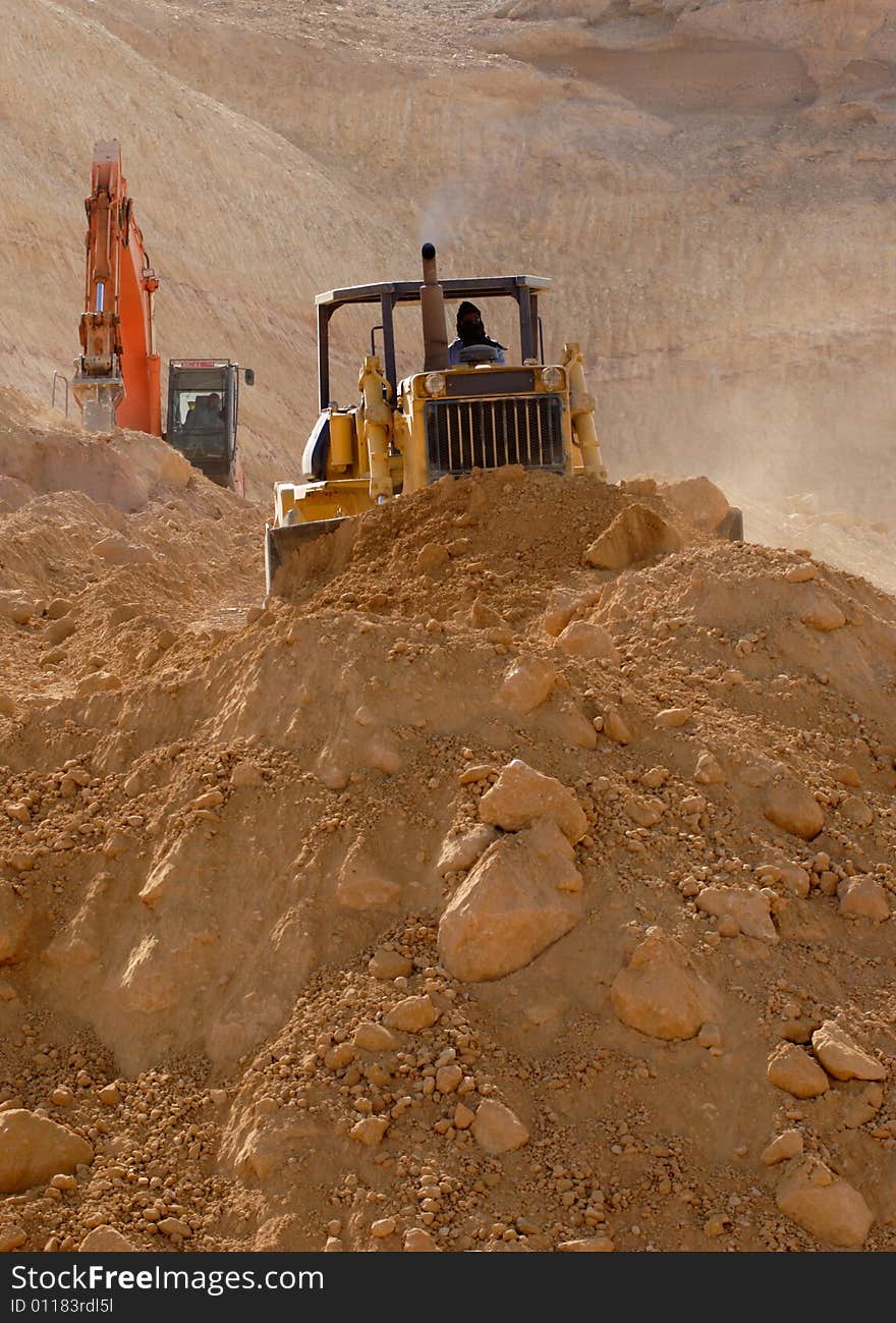 A man with covered nose and mouth operating an earthmover. A man with covered nose and mouth operating an earthmover