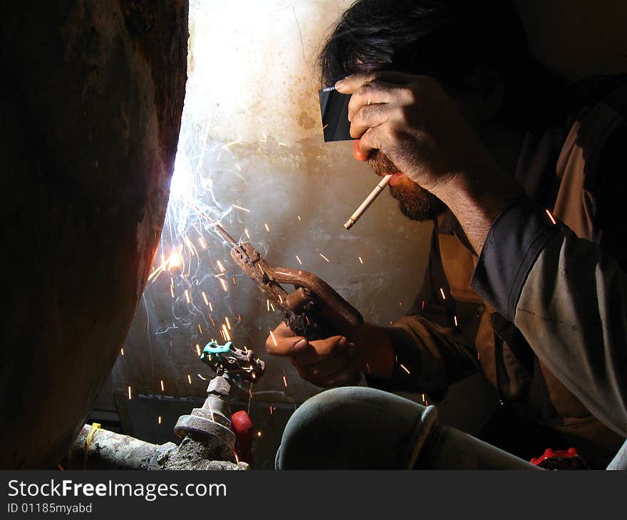 Smoking welder at work without complete protective tools