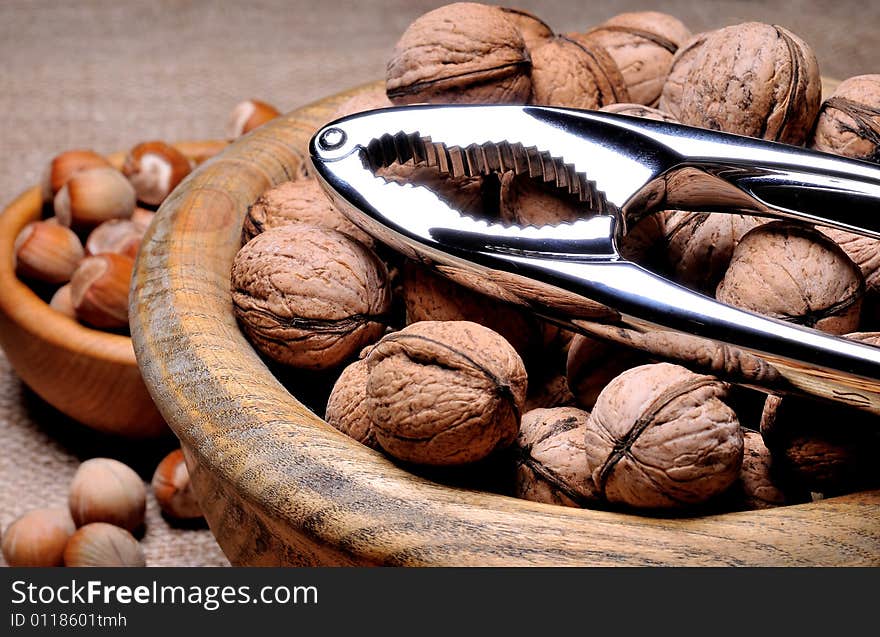 Mixed nuts in bowl with nut cracker on burlap background